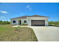 Charming single-story home featuring a two-car garage, neutral stucco, and a well-manicured lawn at 2021 Valencia Dr, Indian Lake Estates, FL 33855