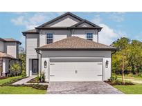Two-story home featuring a two-car garage, complemented by well-manicured landscaping, and a charming entryway at 7688 Somersworth Dr, Kissimmee, FL 34747