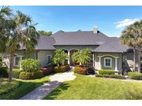 Stunning home with a manicured lawn, lush landscaping, and a grand entrance with palm trees, bushes and inviting walkway at 2660 Wyndsor Oaks Way, Winter Haven, FL 33884