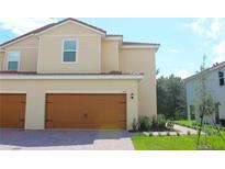 Beige two-story home featuring a two-car garage and a red tile roof at 587 Bay Leaf Dr, Poinciana, FL 34759