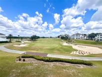 Scenic view of a lush golf course with sand traps and mature trees under a blue sky with fluffy clouds at 7673 Heritage Crossing Way # 202, Reunion, FL 34747