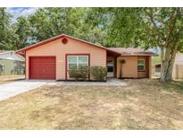 Charming single-story home with a well-maintained lawn and a red garage door at 1313 Periwinkle Ct, Lakeland, FL 33811