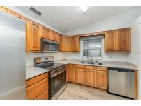 Modern kitchen with stainless steel appliances, wood cabinets, and ample countertop space at 1313 Periwinkle Ct, Lakeland, FL 33811
