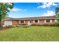 Charming brick home featuring a well-manicured lawn and bright white trim around the windows at 424 Forest Glen Ave, Lakeland, FL 33813