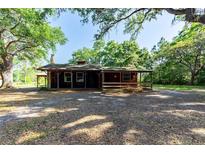 Charming single-story home with rustic wood exterior, front porch, and mature trees in a serene setting at 1836 Cr 609B, Bushnell, FL 33513