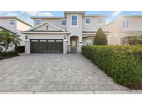 Charming two-story home featuring a paved driveway, a two-car garage, and lush landscaping at 7682 Fairfax Dr, Kissimmee, FL 34747