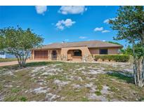 A single-story home featuring a stucco exterior, stone accents, and a well-maintained front lawn at 6531 Red Grange Blvd, Indian Lake Estates, FL 33855