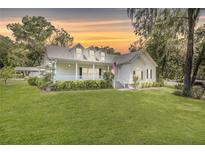 Charming two-story home with a welcoming front porch, well-maintained lawn, and a beautiful, colorful sunset at 7165 Cr 655, Bushnell, FL 33513