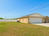 View of the house's side and two car garage with a big backyard with a white fence at 1 Pecan Course Cir, Ocala, FL 34472