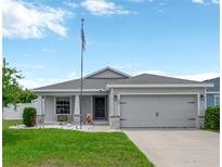 Charming single Gathering home with a well-manicured lawn, gray paint, and a two-car garage at 305 St Georges Cir, Eagle Lake, FL 33839