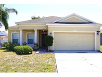 Charming single-story home with a two-car garage and well-maintained lawn and neutral exterior at 1886 Van Gogh Dr, Auburndale, FL 33823