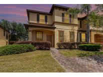 Charming two-story home with stucco exterior, dark shutters and landscaped front yard with brick pathway at 140 Napoli Dr, Davenport, FL 33897