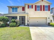 Charming two-story home featuring red shutters, a well-manicured lawn, and an attached two-car garage at 159 Lazy Willow Dr, Davenport, FL 33897