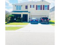 Two-story home featuring a two-car garage, well-maintained lawn and driveway with two parked cars at 159 Lazy Willow Dr, Davenport, FL 33897