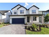 Charming two-story home with a blue garage door and stone-accented columns at 16994 Cedar Valley Cir, Clermont, FL 34711
