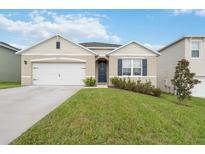 Inviting single-story home featuring a two-car garage, manicured lawn, and charming front entrance at 9532 Black Walnut Dr, Clermont, FL 34715
