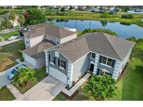 An aerial view of a two-story home with a gray exterior, black shutters, two-car garage, and a pond view at 1322 Aguacate Ct, Orlando, FL 32837