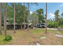 Spacious brown home with an RV parked on the side, surrounded by trees and a large front yard at 3807 Timberlake N Rd, Lakeland, FL 33810