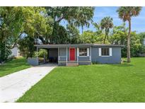 Charming single story home featuring a manicured lawn, a carport and a bright red front door at 1727 Bonita Ave, Orlando, FL 32805