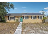 Charming home with solar panels, light yellow stucco, black shutters, and a bright blue front door at 503 Holt Cir, Winter Haven, FL 33880