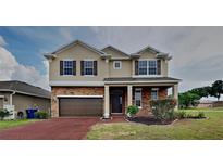 Charming two-story home featuring a stone facade, attached two-car garage, and well-manicured landscaping at 3002 Sunscape Ter, Groveland, FL 34736