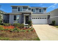 Two-story home featuring a two-car garage, stone accents, and neatly landscaped front yard at 1123 Sugarwood St, Davenport, FL 33837