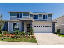 Charming two-story home with blue and gray accents, a two-car garage, and well-maintained landscaping at 1123 Sugarwood St, Davenport, FL 33837