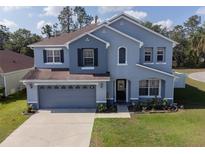 Charming blue two-story home with well-manicured lawn and attached two-car garage at 3125 Kearns Rd, Mulberry, FL 33860