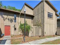 Two-story townhome featuring a neutral exterior, a vibrant red front door, and a well-maintained yard at 4836 Pebble Beach Dr, Orlando, FL 32811