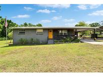 Charming single-story home with a welcoming yellow front door, lush lawn, and convenient carport at 4145 Willow Oak Rd, Mulberry, FL 33860