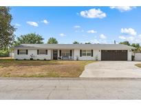 Charming single-story white brick home with a well-maintained yard and attached garage at 455 W Plumosa St, Bartow, FL 33830