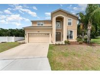 Charming two-story home with a two-car garage, arched entryway, and lush green lawn and mature landscaping at 2721 Stonewood Dr, Lakeland, FL 33810