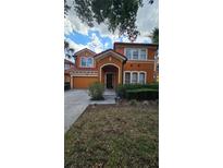 Charming two-story home with a terracotta roof, landscaped front yard and an attached two-car garage at 153 Tigerlily Ct, Davenport, FL 33837