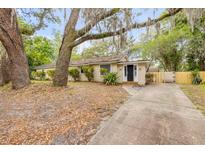 Charming single-story home with a black front door, mature trees, and a long driveway at 110 E Lauren Ct, Fern Park, FL 32730