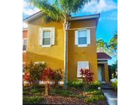 Inviting two-story home featuring a lush landscaped yard, vibrant plants, and a stately palm tree at 4720 Vero Beach Pl, Kissimmee, FL 34746