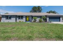 Charming gray home featuring a bright yellow front door and a well-maintained green lawn at 1416 Leighton Ave, Lakeland, FL 33803