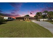 Traditional-style home with a large front yard, two-car garage, RV, and American flag displayed at 1716 Bayou Cir, Lakeland, FL 33803