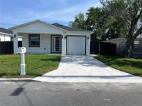 Charming single-story home with a well-manicured lawn and a driveway leading to an attached garage at 209 W 6Th St, Lakeland, FL 33805