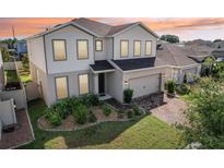 Charming two-story home with a well-manicured lawn and brick-paved driveway, showcasing its inviting curb appeal at 392 Summer Squall Rd, Davenport, FL 33837