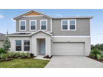 Charming two-story home with light-gray siding, a two-car garage, and a well-manicured front yard at 1205 Tidal St, Haines City, FL 33844