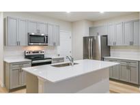Modern kitchen features stainless steel appliances, gray cabinets, and a center island with a white countertop at 3775 King Hill Dr, Haines City, FL 33844