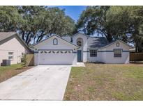 Charming single-Gathering home featuring a two-car garage, blue trim, and beautiful mature trees at 748 Sagewood Dr, Lakeland, FL 33813