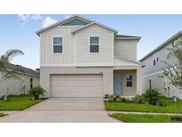 Charming two-story home showcasing a well-maintained lawn, attached garage, and a cheerful light blue front door at 4027 Gardenia Ave, Lake Hamilton, FL 33851