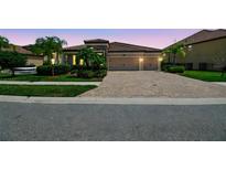 Charming single-story home with a brick driveway, tile roof, manicured landscaping, and a two-car garage at 1839 Via Lago Dr, Lakeland, FL 33810