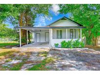 Charming single-story home with a carport and a screened-in porch, surrounded by lush greenery at 211 W Crescent Dr, Lakeland, FL 33805