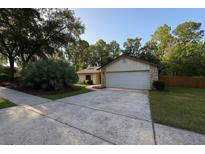 Charming single-story home featuring a well-manicured lawn, mature trees and a concrete driveway at 205 Hickory Dr, Longwood, FL 32779