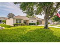 Charming single-story home featuring a well-manicured lawn, mature trees, and a side-entry two-car garage at 9345 Se 171St Le Flore Ln, The Villages, FL 32162