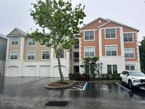 Three-story condominium building with brick and siding, tree, and handicap parking at 12849 Madison Pointe Cir # 204, Orlando, FL 32821