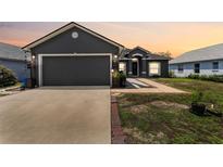 Charming gray home showcasing a two-car garage, front door, manicured lawn, and beautiful brick-lined walkway at 181 Osprey Heights Dr, Winter Haven, FL 33880