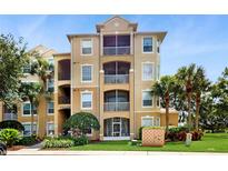 Beautiful tan condo building with mature landscaping, a well-manicured lawn, and inviting covered patios at 7654 Comrow St # 202, Kissimmee, FL 34747